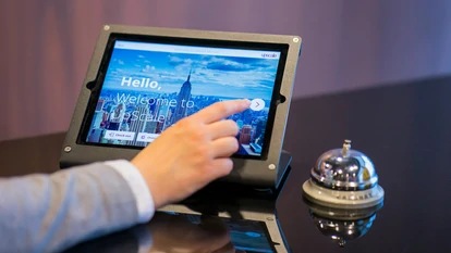  Man typing ona tablet at the frond desk of an hotel